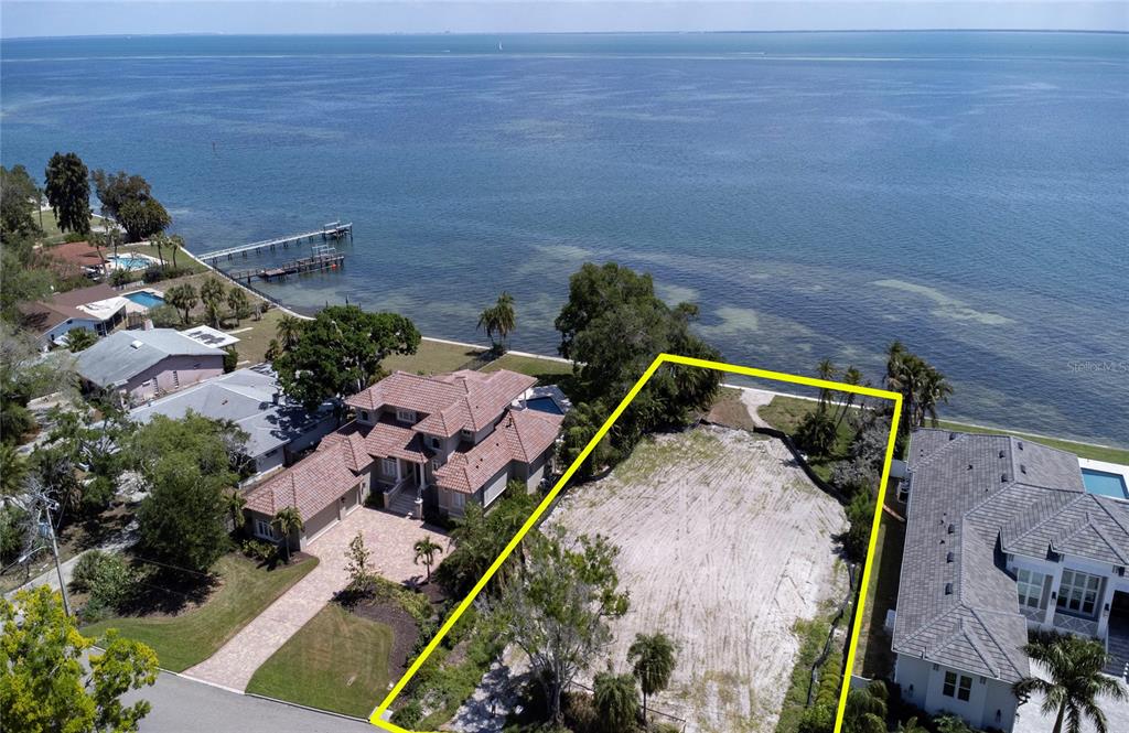An aerial view shows a vacant waterfront lot outlined in yellow between two residential houses — 5926 BAHAMA SHORES DRIVE S, ST PETERSBURG, FL