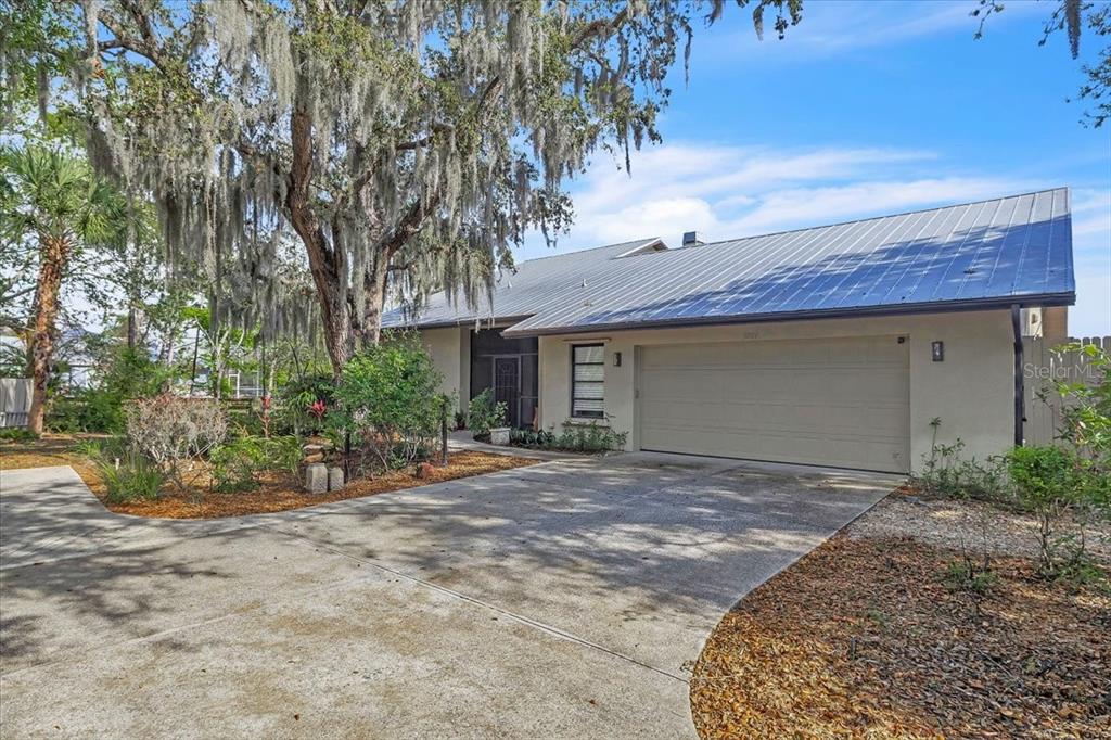 A single-story house with a metal roof, two-car garage, and a large moss-covered oak tree — 3264 PARK DRIVE, PUNTA GORDA, FL
