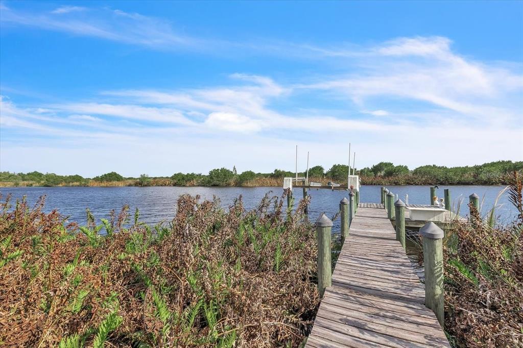 A wooden dock extends into a calm body of water surrounded by dense green vegetation — 3264 PARK DRIVE, PUNTA GORDA, FL