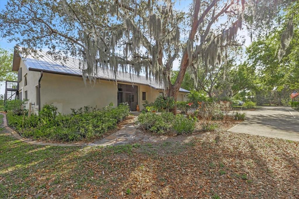 A beige house with a metal roof sits behind a large tree with Spanish moss — 3264 PARK DRIVE, PUNTA GORDA, FL