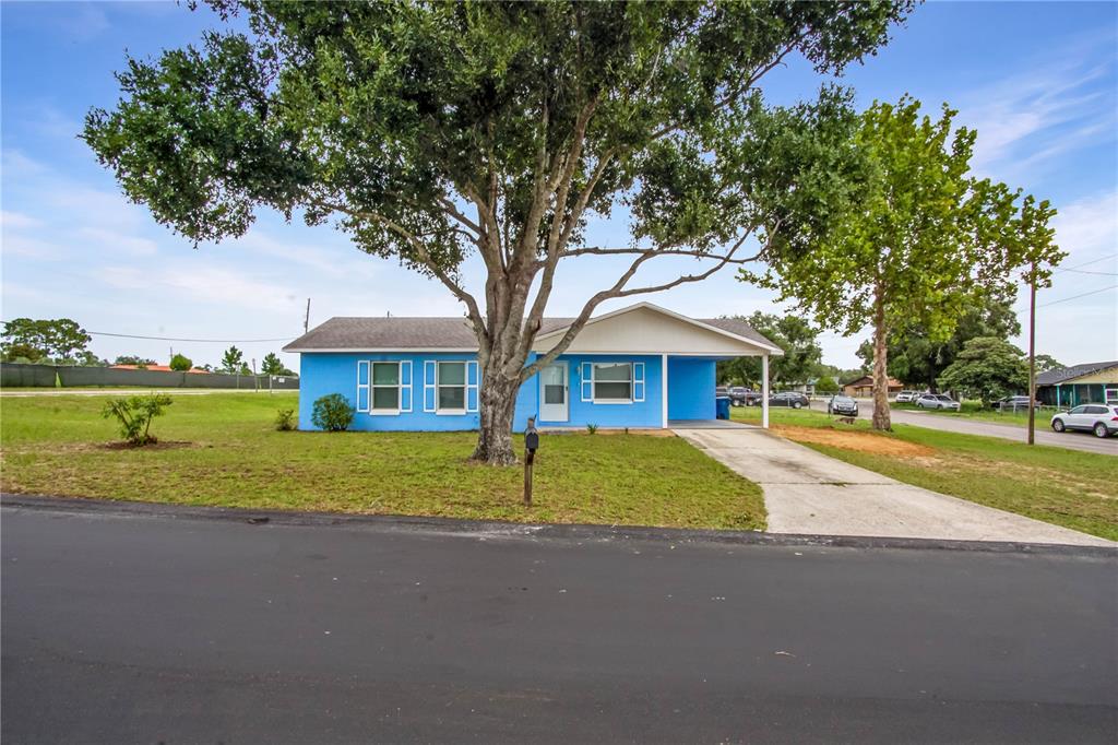 A blue single-story house with a front porch and a large tree in the yard — 1000 VALENCIA AVENUE, HAINES CITY, FL