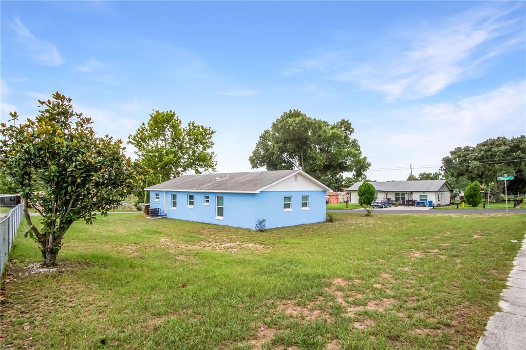 A light blue single-story house sits on a grassy lot with a large tree nearby — 1000 VALENCIA AVENUE, HAINES CITY, FL