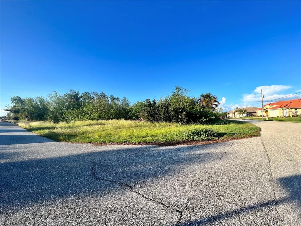 A vacant, grassy corner lot sits at the intersection of two paved residential streets — 13468 RAYBURN LANE, PORT CHARLOTTE, FL