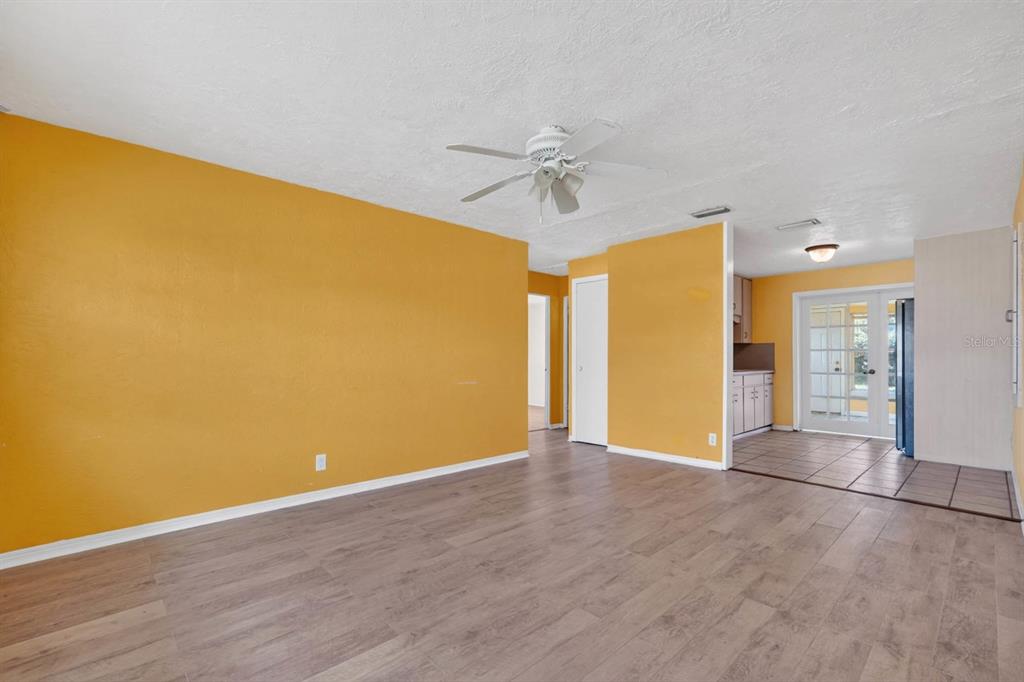 A living room with yellow walls, wood-look flooring, a ceiling fan, and an adjacent kitchen — 39 MARGARET ROAD, ORMOND BEACH, FL