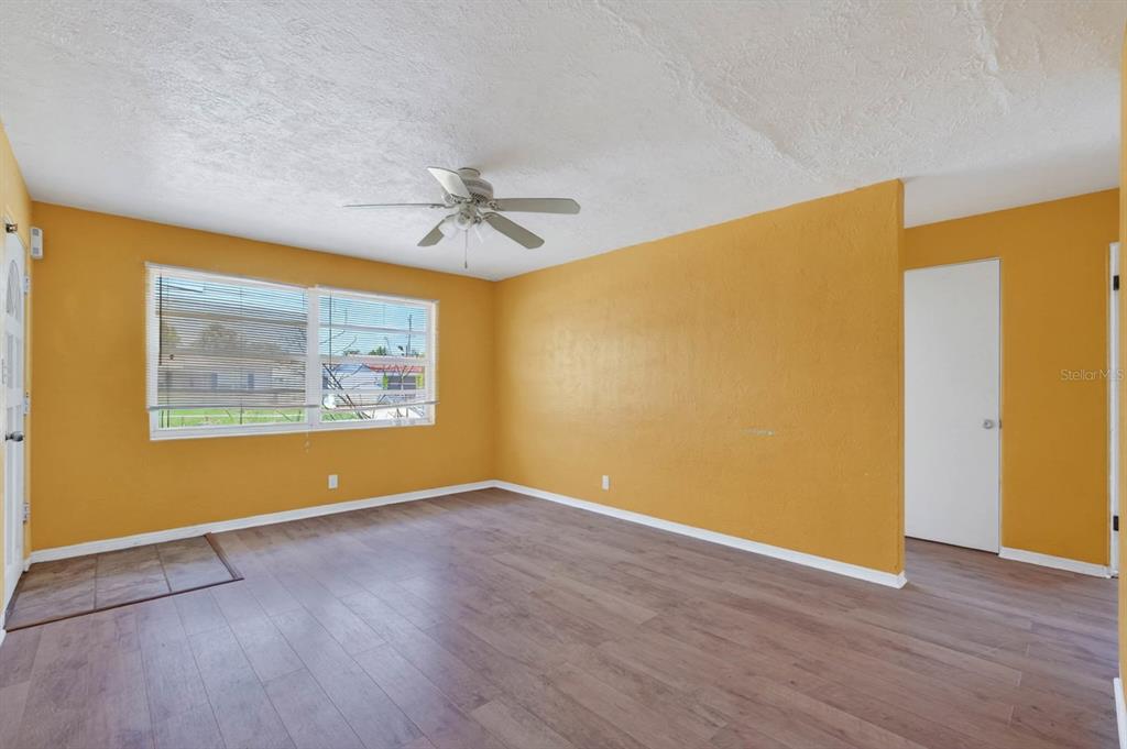 An empty room with yellow walls, wood-look flooring, a ceiling fan, and a window — 39 MARGARET ROAD, ORMOND BEACH, FL