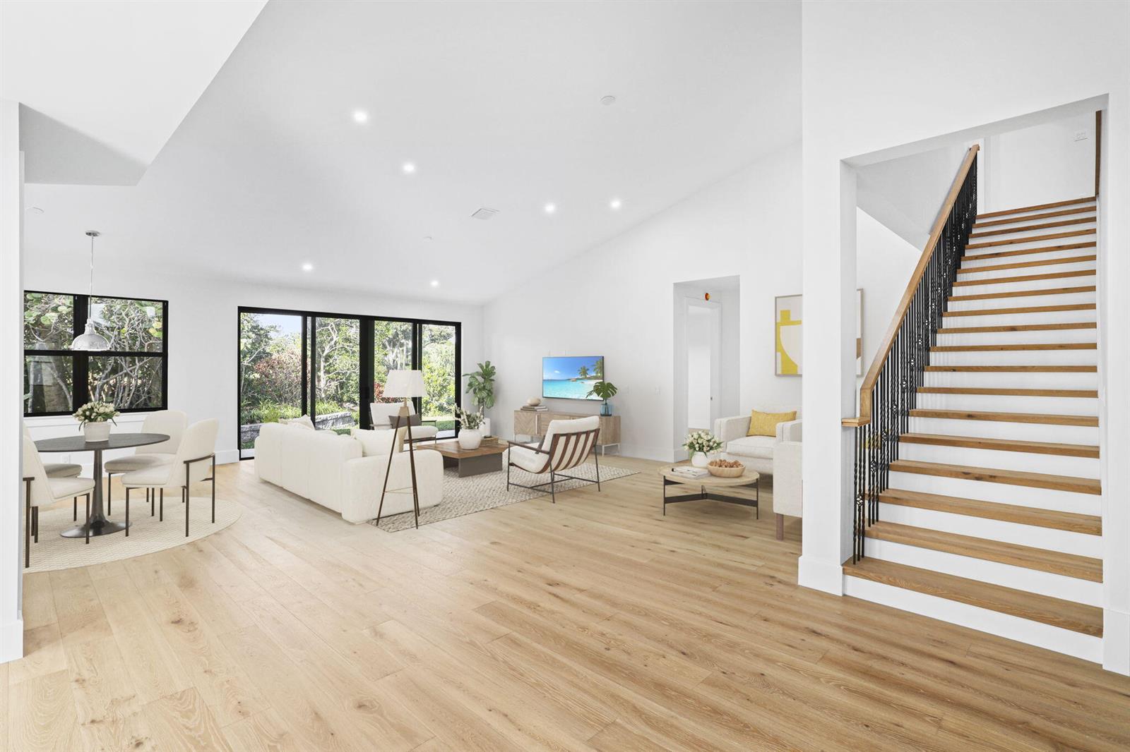 A bright, open-concept living and dining area features light wood floors and a wooden staircase — 195 Birkdale Lane, Jupiter FL 33458, JUPITER, FL