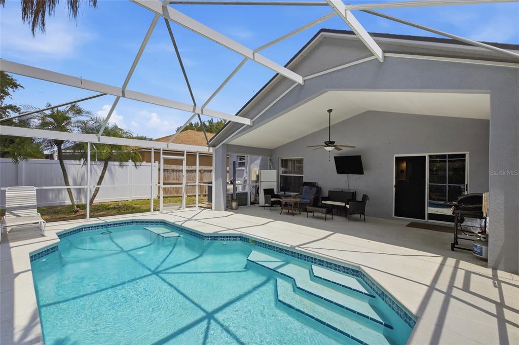 A screened-in patio features a swimming pool with steps and outdoor furniture under a roof — 7611 WILTSHIRE PARK PLACE, APOLLO BEACH, FL