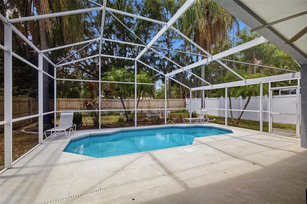 A screened-in pool patio features a concrete deck, lounge chairs, and a fenced backyard — 7611 WILTSHIRE PARK PLACE, APOLLO BEACH, FL
