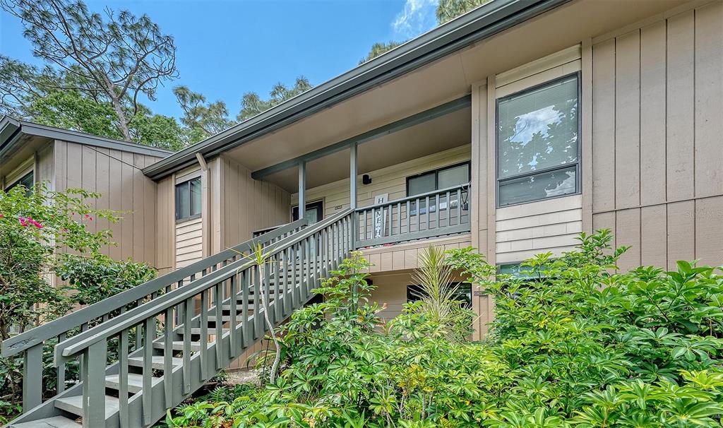 An exterior view of a two-story apartment building with wooden stairs leading to the balcony — 1720 GLENHOUSE DRIVE UNIT 326, SARASOTA, FL