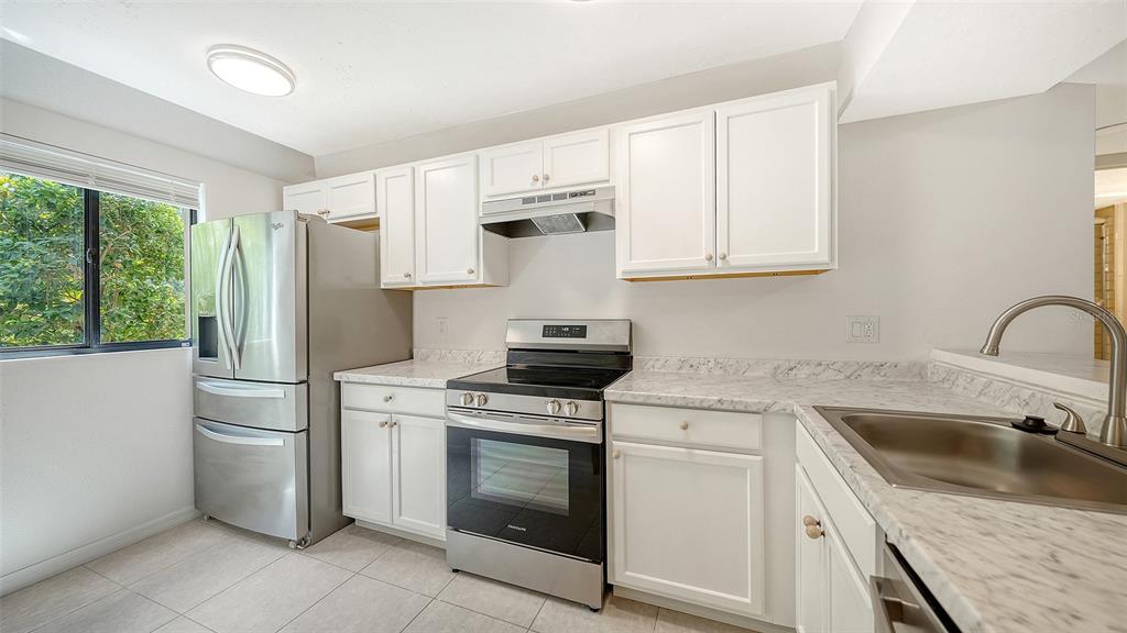 A kitchen features white cabinets, stainless steel appliances, and marble-look countertops — 1720 GLENHOUSE DRIVE UNIT 326, SARASOTA, FL