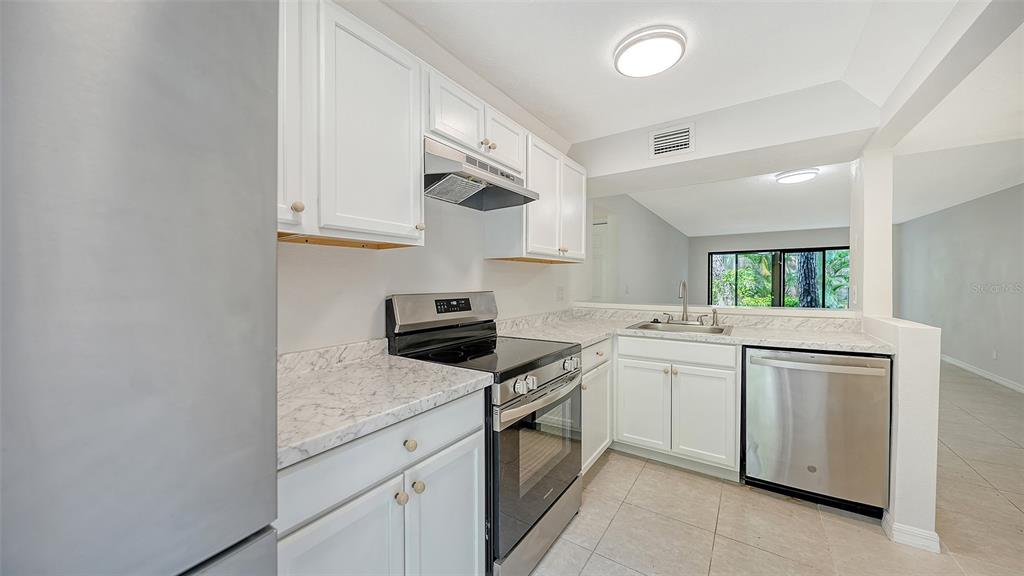 A kitchen features white cabinets, stainless steel appliances, and marble-look countertops — 1720 GLENHOUSE DRIVE UNIT 326, SARASOTA, FL