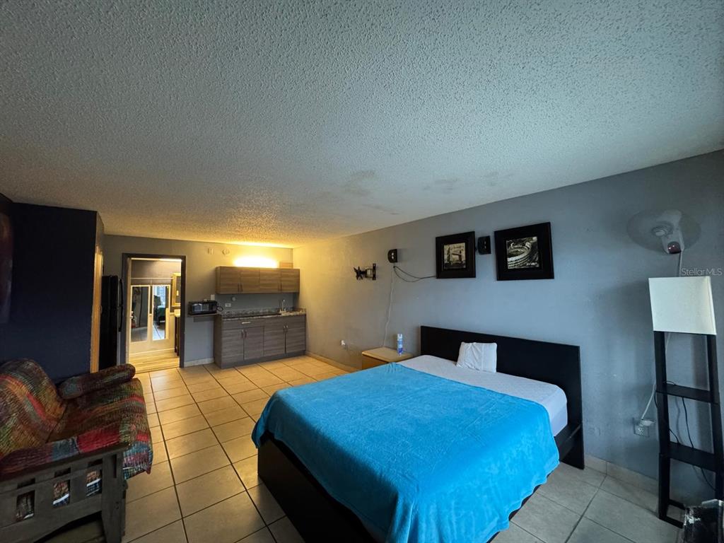 A studio apartment featuring a bed, a small kitchenette, a sofa, and tiled flooring — 8421 S ORANGE BLOSSOM TRAIL UNIT 420, ORLANDO, FL