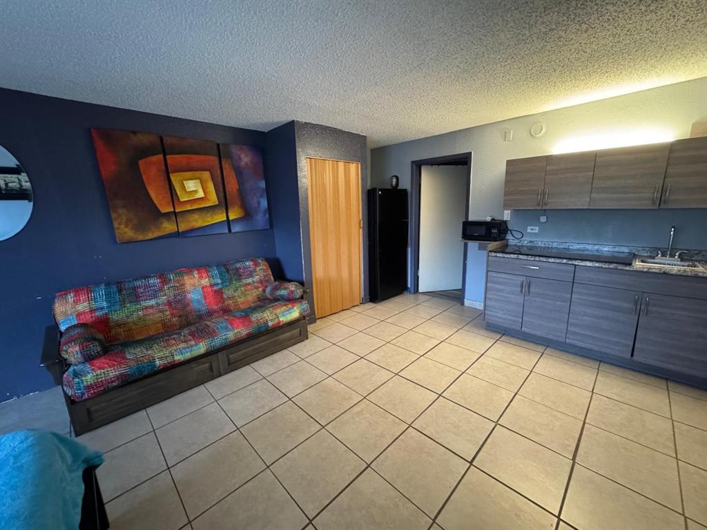 A studio apartment featuring a colorful sofa, dark wood cabinets, and light-colored tile flooring — 8421 S ORANGE BLOSSOM TRAIL UNIT 420, ORLANDO, FL