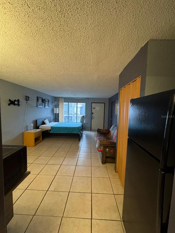 A studio apartment features tile flooring, a bed, a sofa, and a black refrigerator — 8421 S ORANGE BLOSSOM TRAIL UNIT 420, ORLANDO, FL