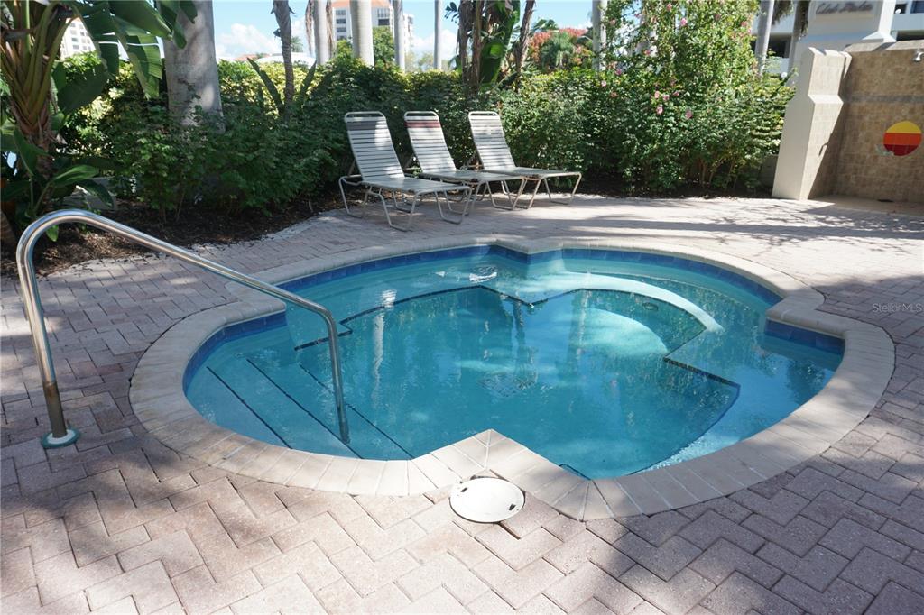 A round hot tub with a metal handrail sits on a brick patio with lounge chairs — 6093 BAHIA DEL MAR CIRCLE UNIT 277, ST PETERSBURG, FL