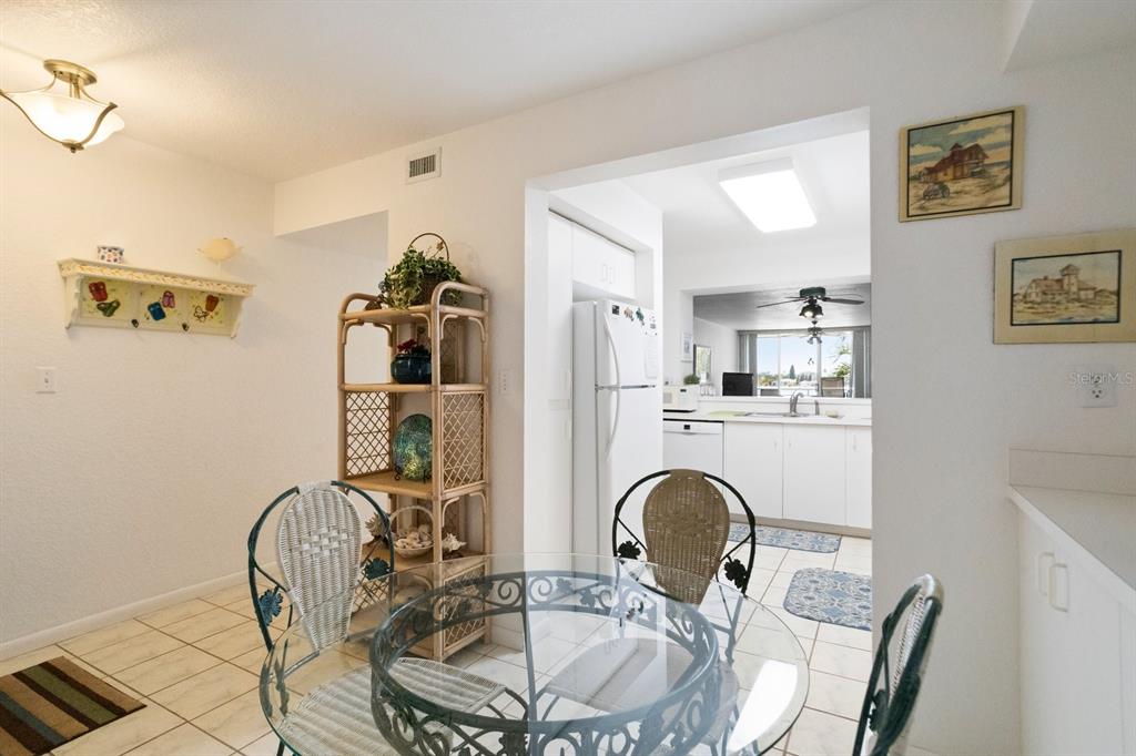 A dining area with a glass table and wicker chairs leads into a white kitchen — 6093 BAHIA DEL MAR CIRCLE UNIT 277, ST PETERSBURG, FL