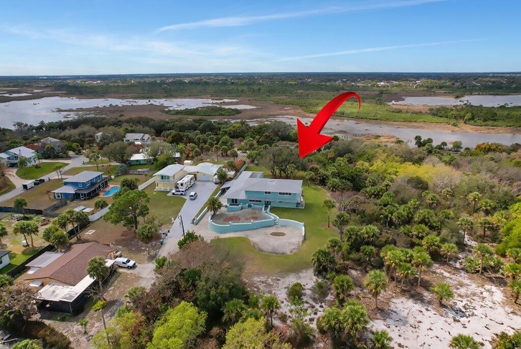 An aerial view shows a light blue house with a large yard and surrounding vegetation — 3712 E Mockingbird Hill, Jensen Beach FL 34957, JENSEN BEACH, FL