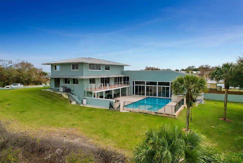 An aerial view of a two-story light green house with a swimming pool and lawn — 3712 E Mockingbird Hill, Jensen Beach FL 34957, JENSEN BEACH, FL