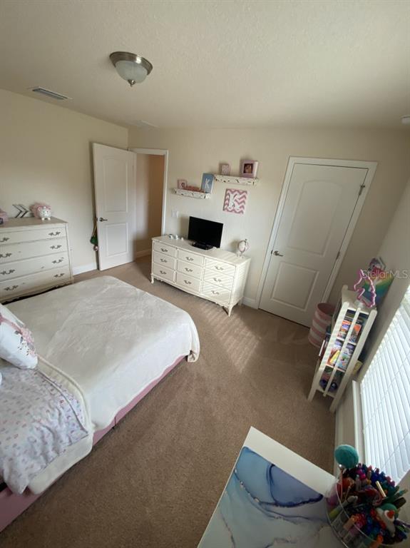A bedroom features a bed, two white dressers, a small television, and a bookshelf — 4634 SE 27TH STREET, OCALA, FL