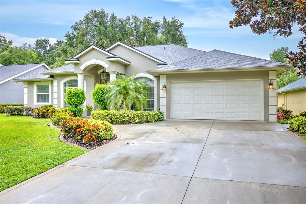 A single-story house with a beige stucco exterior, a two-car garage, and landscaped front yard — 188 HUNTLEY OAKS BOULEVARD, LAKE PLACID, FL