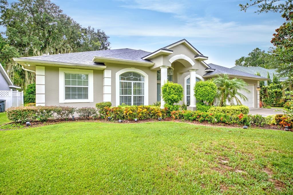 A single-story house with a beige stucco exterior, arched entryway, and a manicured front lawn — 188 HUNTLEY OAKS BOULEVARD, LAKE PLACID, FL
