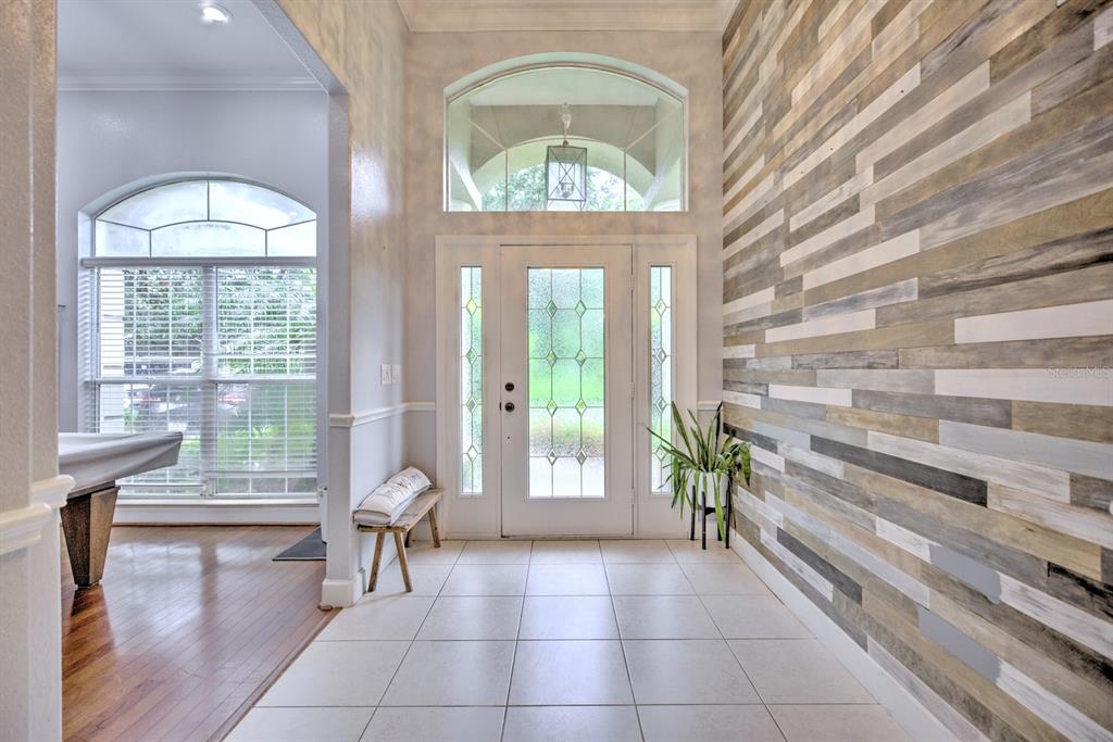 An entryway features a tiled floor, a wood-paneled accent wall, and a glass-paneled front door — 188 HUNTLEY OAKS BOULEVARD, LAKE PLACID, FL