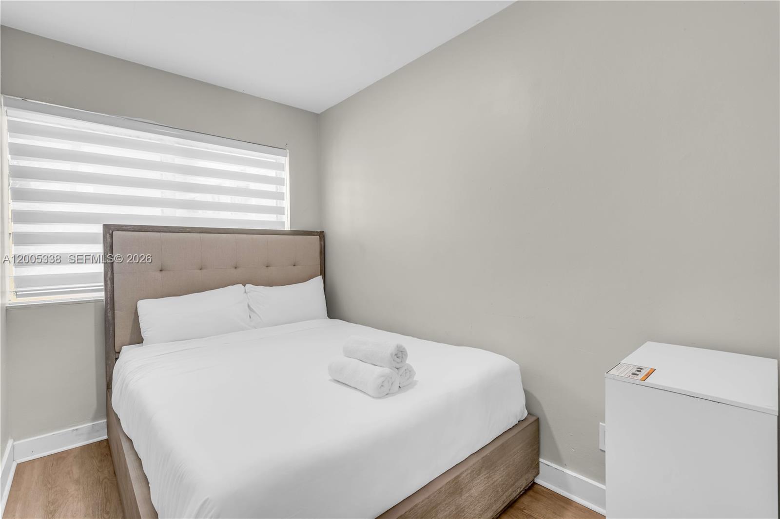A bedroom features a bed with a tufted headboard, white bedding, and a window — 10006 E Bay Harbor Dr # 16, Bay Harbor Islands FL 33154, BAY HARBOR ISLANDS, FL