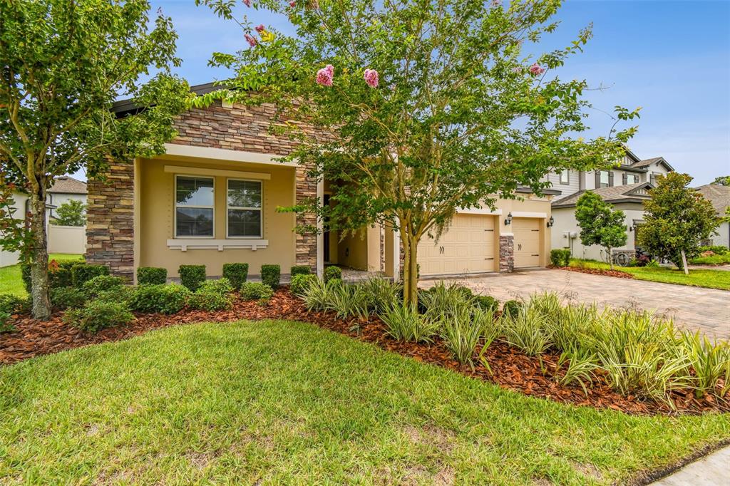 A single-story house with a stone facade, beige stucco, and a paved driveway — 4512 TATUM LOOP, ODESSA, FL