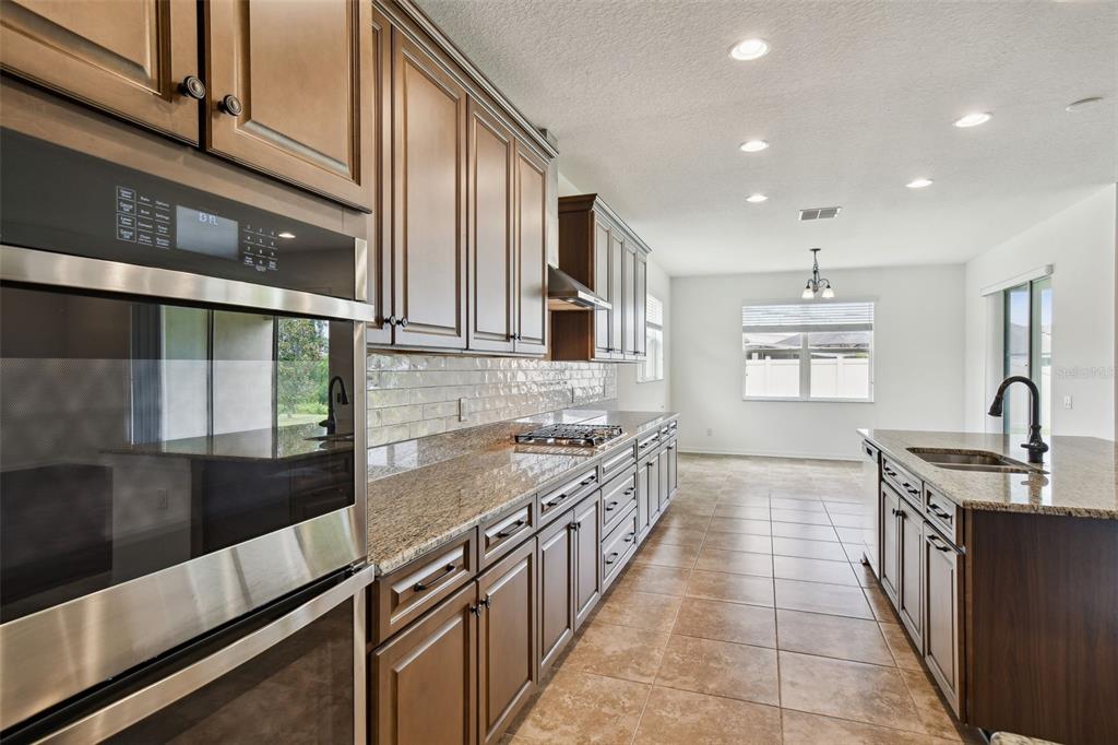 A kitchen features dark wood cabinets, granite countertops, stainless steel appliances, and tile flooring — 4512 TATUM LOOP, ODESSA, FL