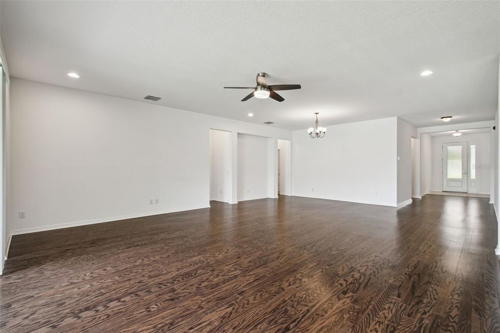 A spacious, empty living area with dark wood flooring, white walls, and a ceiling fan — 4512 TATUM LOOP, ODESSA, FL