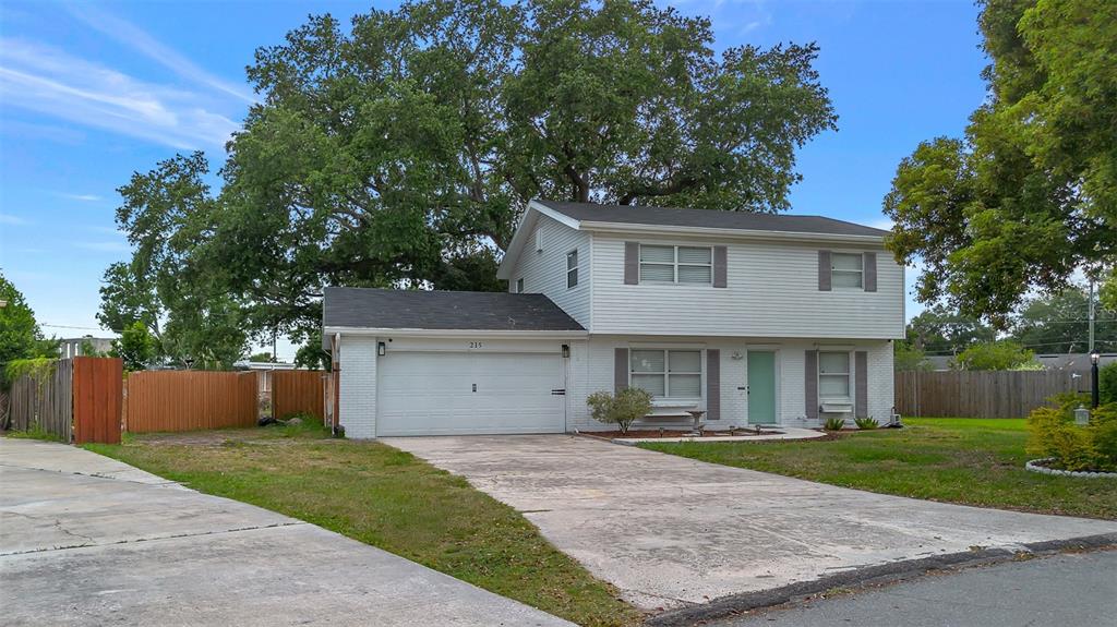 A two-story house with white siding, a brick lower level, and an attached garage — 215 KILMER LANE, WINTER HAVEN, FL