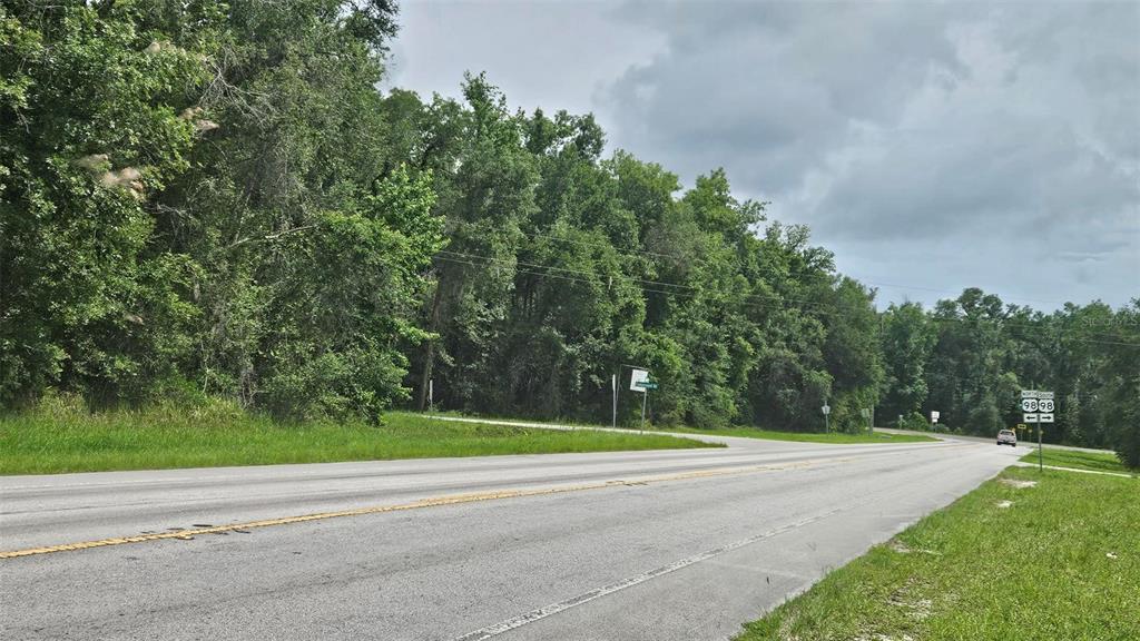 A paved road runs alongside a wooded lot with a highway sign in the distance — 0 COBB ROAD, BROOKSVILLE, FL