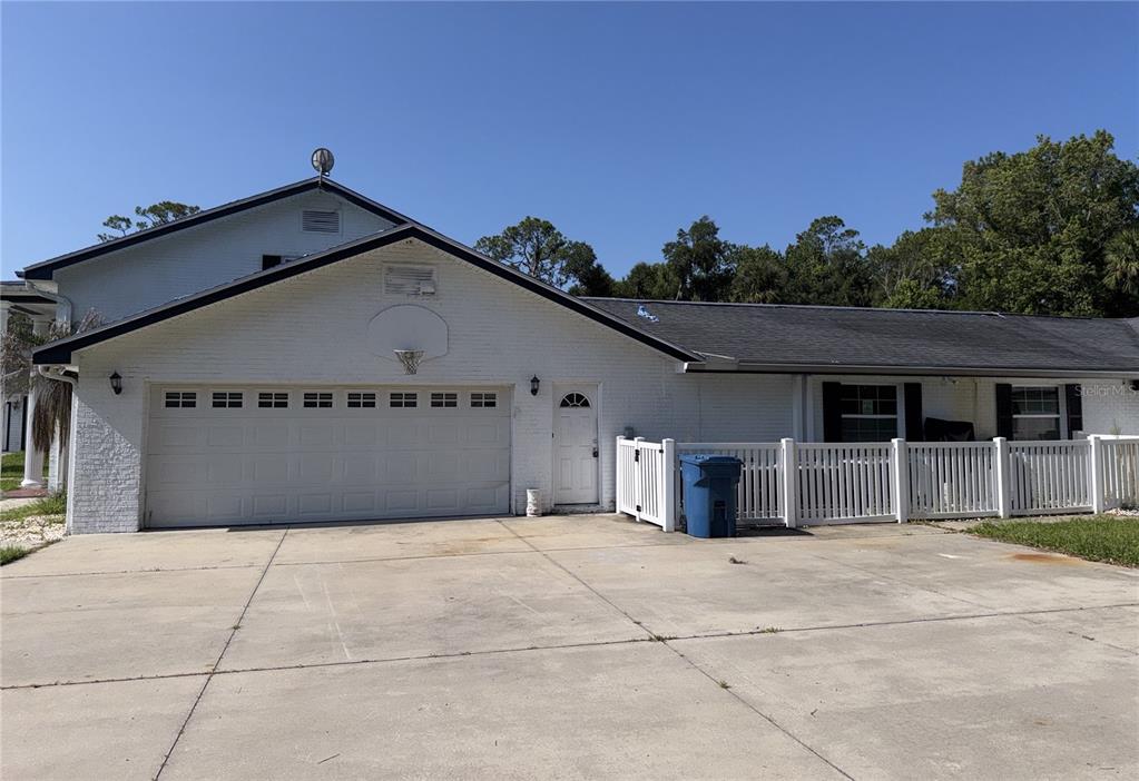 A two-story white house with a columned porch stands behind a large concrete driveway — 2015 HALIFAX DRIVE, PORT ORANGE, FL