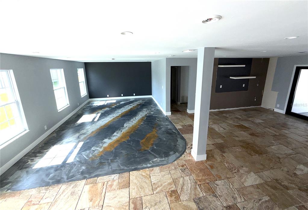 A room with gray walls, a staircase, and a decorative metallic epoxy floor — 2015 HALIFAX DRIVE, PORT ORANGE, FL