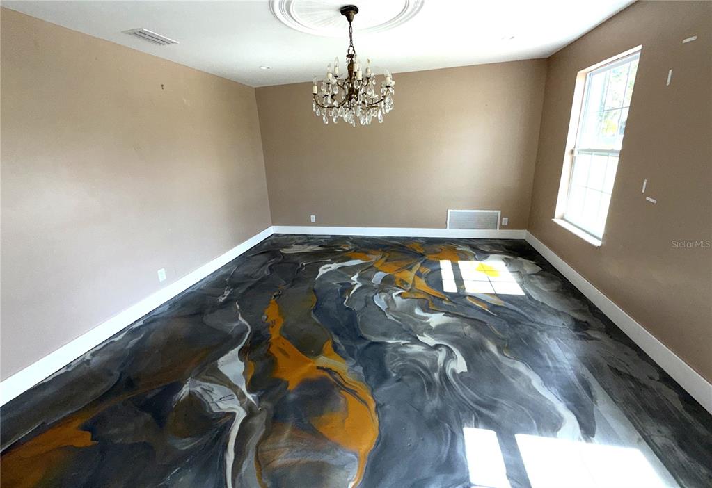 A room with light gray walls, a dark accent wall, and a decorative epoxy floor — 2015 HALIFAX DRIVE, PORT ORANGE, FL