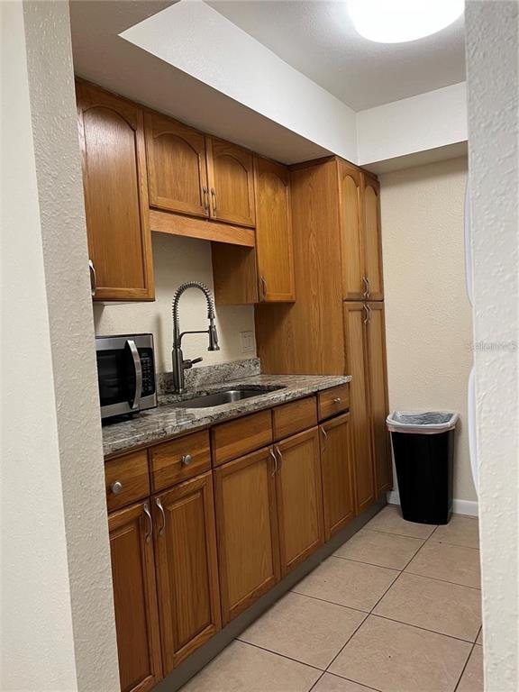 A kitchen features wooden cabinets, granite countertops, a stainless steel sink, and a microwave — 2176 WINCHESTER ROAD N UNIT 2, ST PETERSBURG, FL