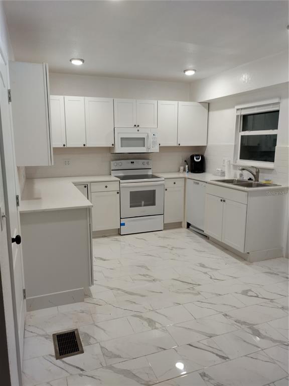 A kitchen with white cabinets, white countertops, and white marble-patterned tile flooring — 405 S RIDGEWOOD AVENUE, DAYTONA BEACH, FL