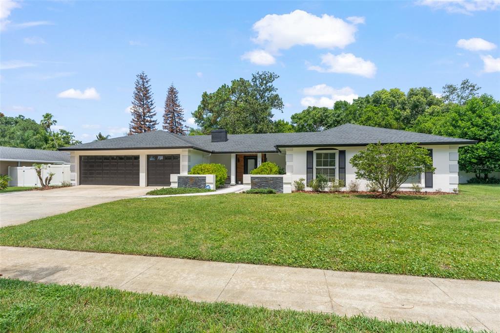 A single-story ranch house with a white exterior, dark roof, and a two-car garage — 131 COUNTRYSIDE DRIVE, LONGWOOD, FL