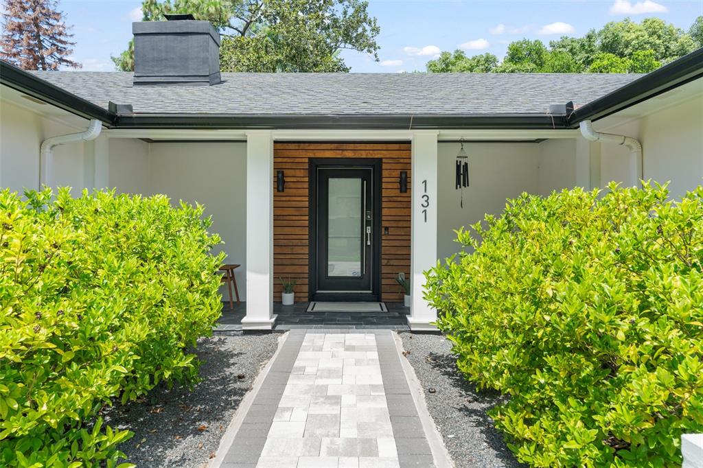 A front entrance features a modern glass door, wood paneling, and a paved walkway — 131 COUNTRYSIDE DRIVE, LONGWOOD, FL