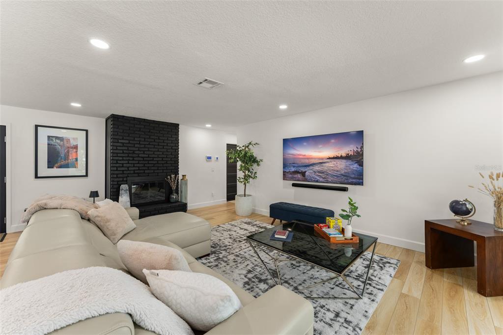 A living room features a light-colored sectional sofa, a black brick fireplace, and a television — 131 COUNTRYSIDE DRIVE, LONGWOOD, FL