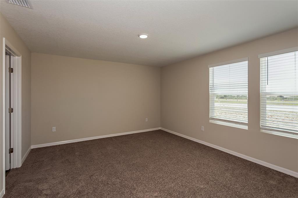 An empty bedroom features beige walls, brown carpet, and two windows with white blinds — 5449 SAN PIETRO DRIVE, WINTER HAVEN, FL