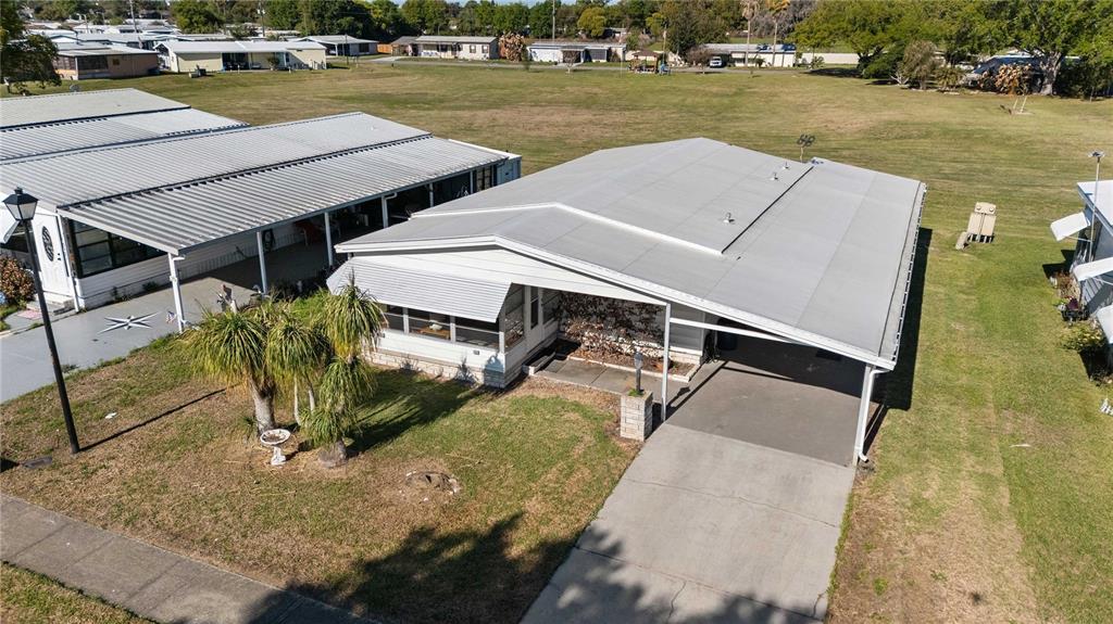 An aerial view shows a single-story mobile home with a metal roof and attached carport — 5427 SEVILLE DRIVE, ZEPHYRHILLS, FL