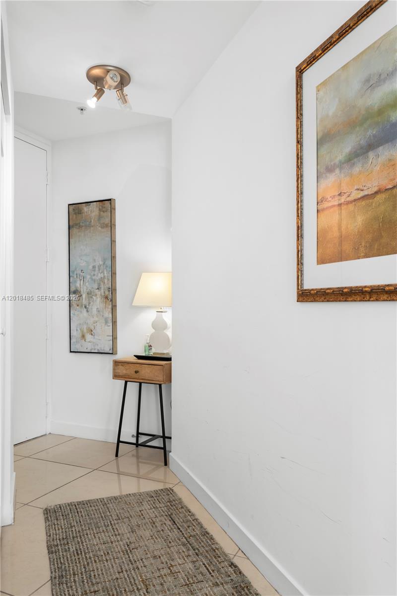 A hallway features white walls, tiled flooring, a small wooden console table, and framed artwork — 1111 SW 1st Ave, Miami FL 33130, MIAMI, FL