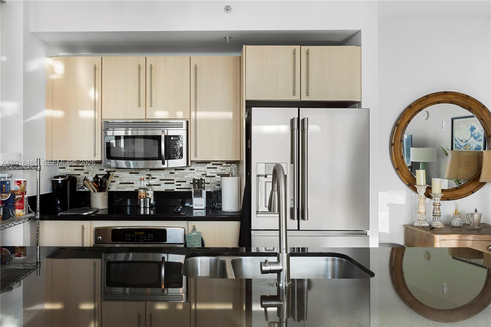 A modern kitchen features light wood cabinets, stainless steel appliances, and a black countertop island — 1111 SW 1st Ave, Miami FL 33130, MIAMI, FL