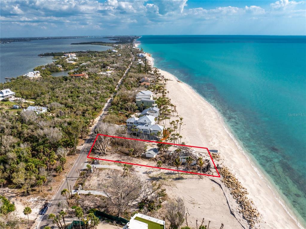 An aerial view shows a vacant beachfront lot outlined in red along a coastal road — 7380 MANASOTA KEY ROAD, ENGLEWOOD, FL