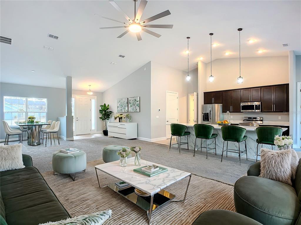 An open-concept living and dining area features a kitchen island, dark cabinetry, and vaulted ceilings — 16 EGAN DRIVE, PALM COAST, FL