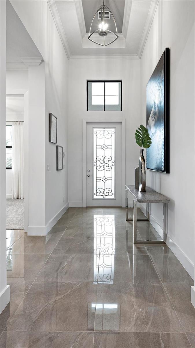 A bright entryway features a decorative glass front door, tile flooring, and a modern pendant light — 1911 SE Royale Preserve Way, Stuart FL 34997, STUART, FL
