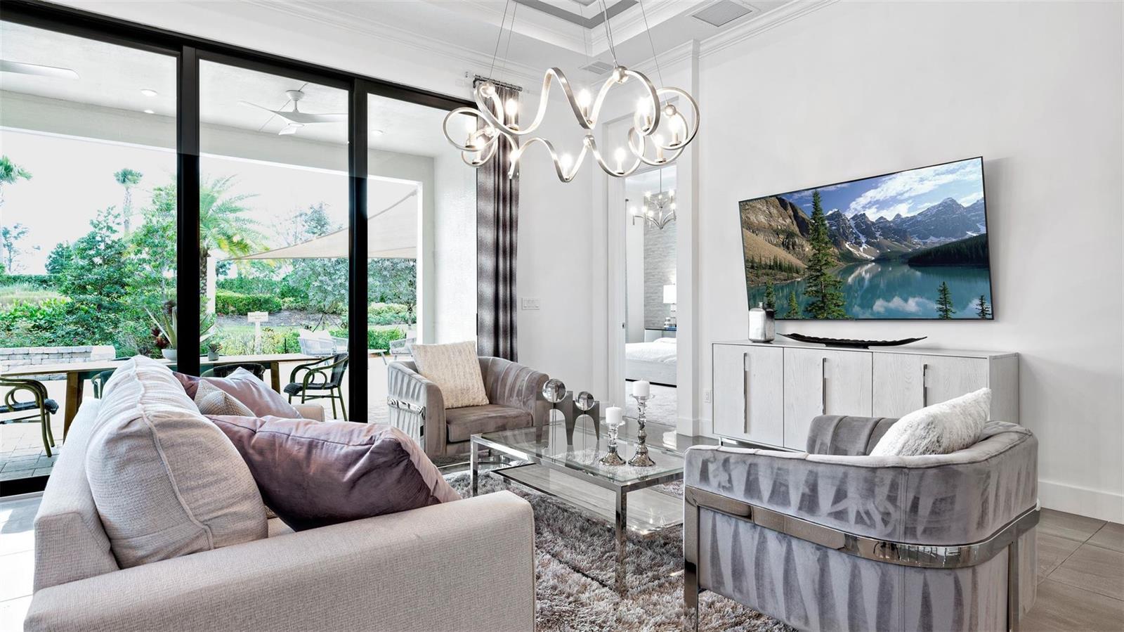 A modern living room features a sofa, two armchairs, a glass coffee table, and a television — 1911 SE Royale Preserve Way, Stuart FL 34997, STUART, FL