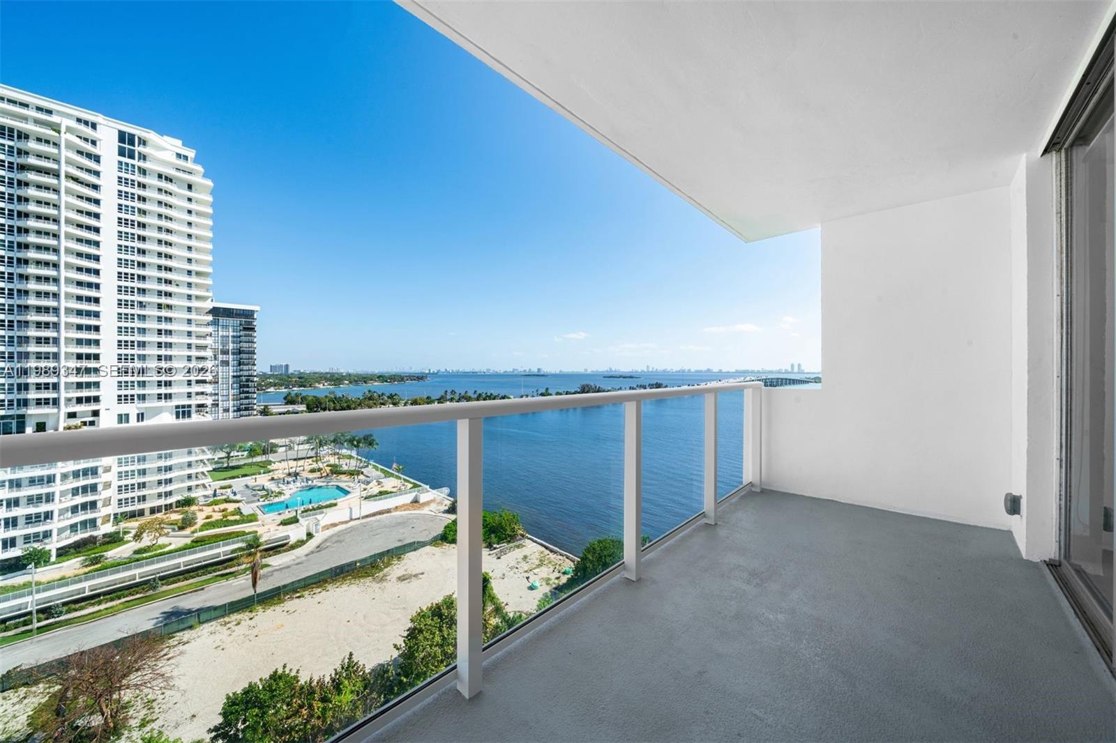 A balcony with a glass railing overlooks a bay, a swimming pool, and high-rise buildings — 3301 NE 5th AVE # 1212, Miami FL 33137, MIAMI, FL