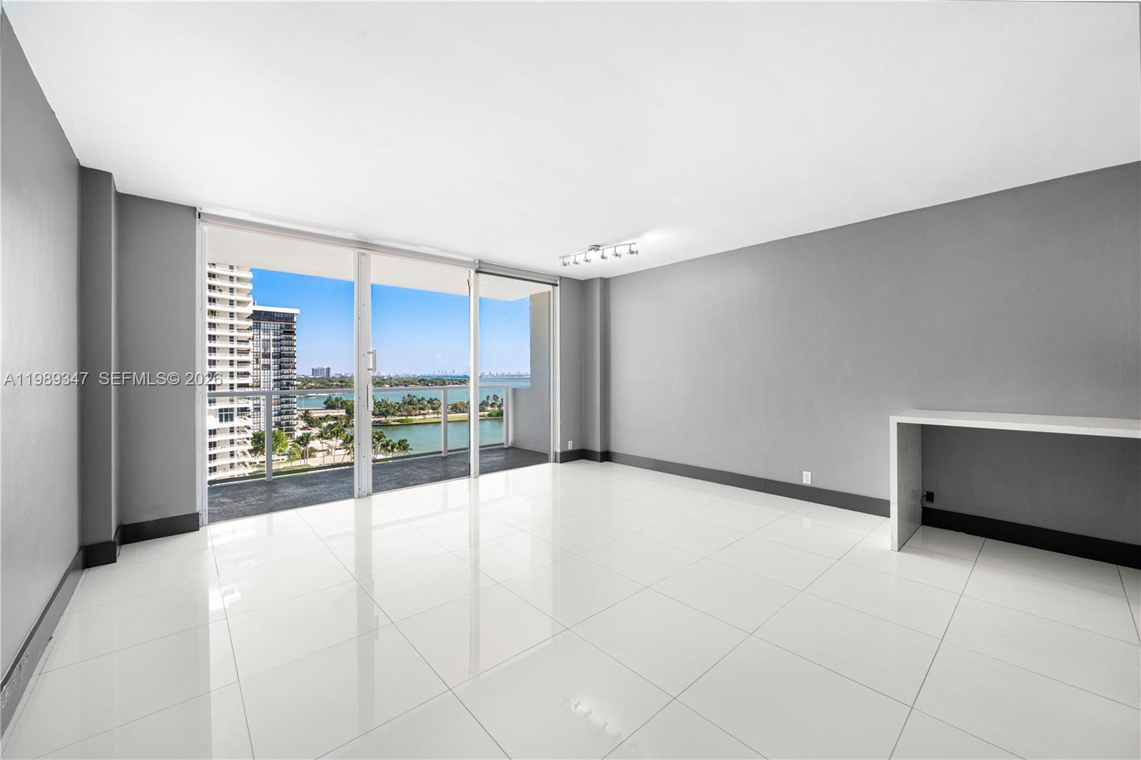 An empty room with gray walls, white tile floors, and a balcony overlooking water — 3301 NE 5th AVE # 1212, Miami FL 33137, MIAMI, FL